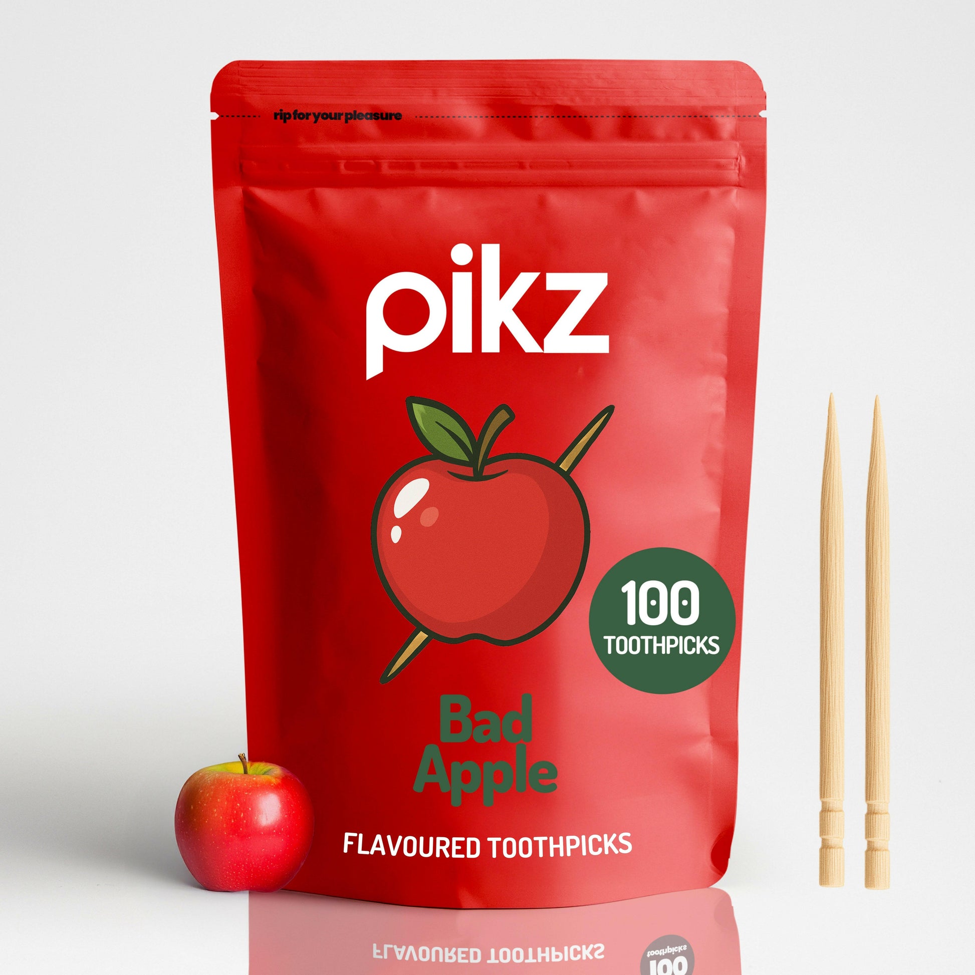 Red package of pikz Bad Apple flavoured toothpicks with an apple and toothpicks on a white background