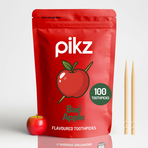 Red package of pikz Bad Apple flavoured toothpicks with an apple and toothpicks on a white background